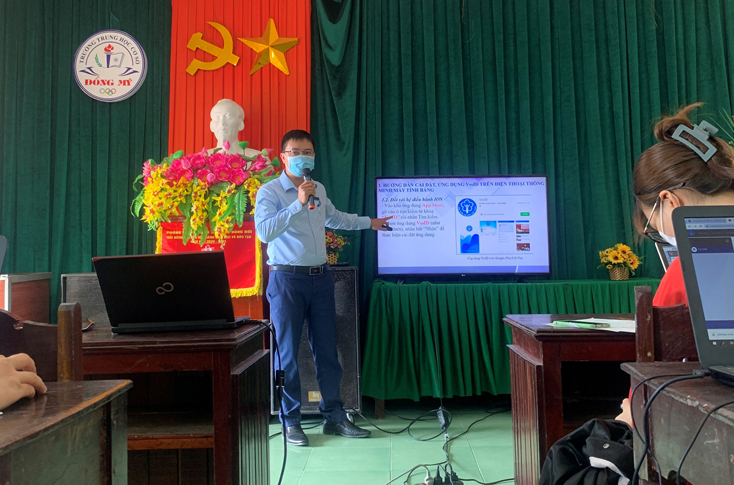 Ông Nguyễn Quang Thuận, Trưởng phòng Công nghệ thông tin (CNTT) BHXH tỉnh Quảng Bình tuyên truyền và hướng dẫn cho giáo viên và phụ huynh học sinh Trường THCS Đồng Mỹ đăng ký tài khoản giao dịch điện tử, cài đặt, sử dụng ứng dụng VssID-BHXH số.