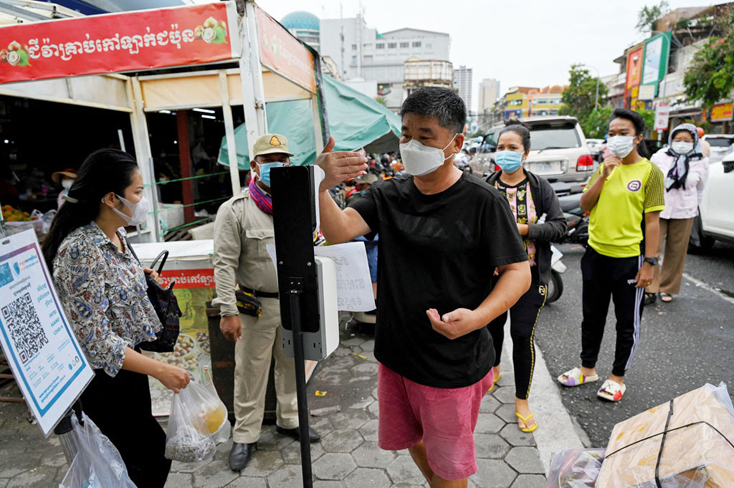 Người dân kiểm tra thân nhiệt tại một chợ ở Phnom Penh sau khi chợ được mở lại -Ảnh AFP