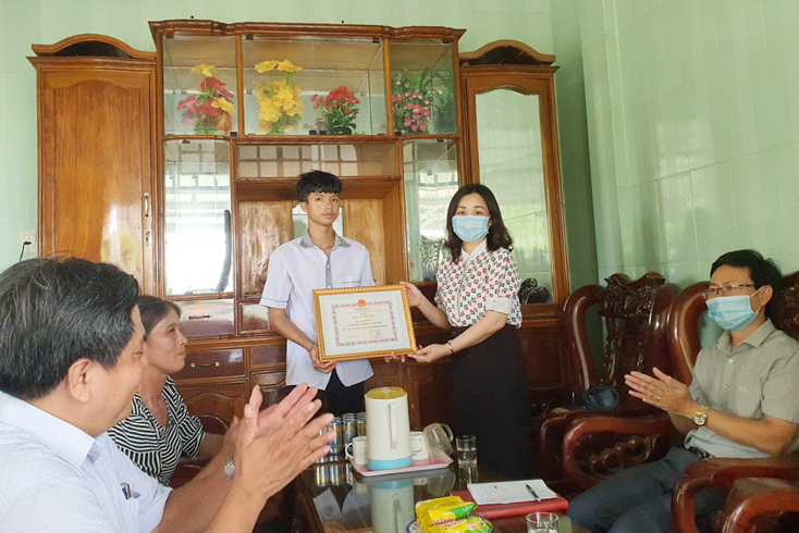 Bà Mai Thị Liên Giang, Phó Giám đốc Sở GD-ĐT Quảng Bình trao tặng giấy khen của Giám đốc Sở GD-ĐT cho em Vũ.