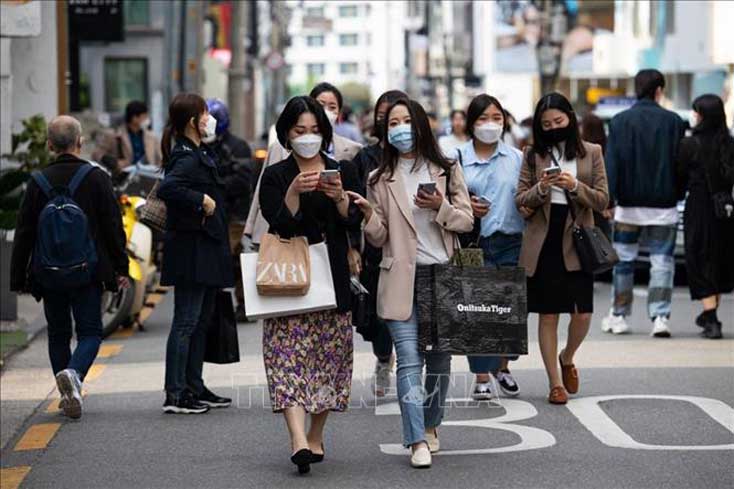Người dân đeo khẩu trang phòng dịch COVID-19 khi đi trên đường phố tại Seoul, Hàn Quốc, ngày 18-4-2021. Ảnh: Bloomberg/TTXVN