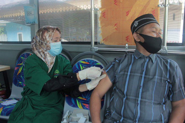 Một người dân được tiêm vaccine COVID-19 bên trong xe buýt công cộng. Ảnh: Reuters