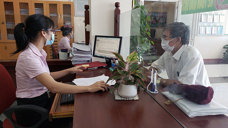 Cán bộ Phòng giao dịch NHCSXH huyện Quảng Trạch giải ngân vốn vay trả lương ngừng việc, trả lương phục hồi sản xuất cho doanh nghiệp trên địa bàn. 