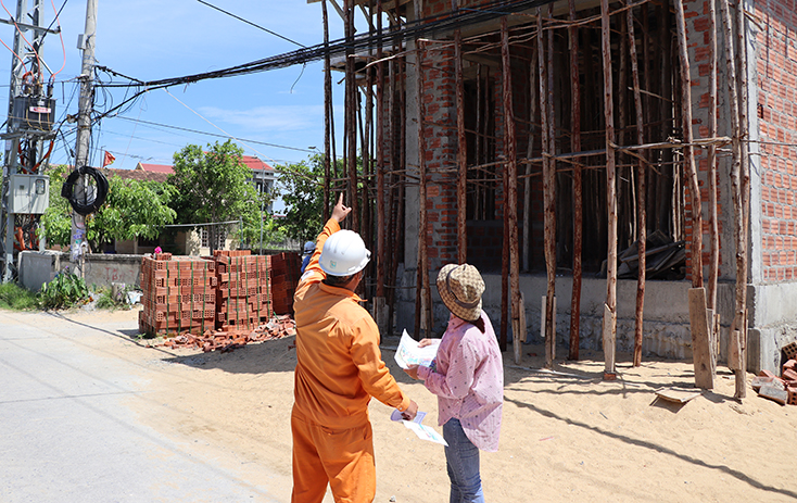 Công nhân PC Quảng Bình hướng dẫn các hộ dân bảo đảm khoảng cách an toàn khi xây dựng công trình dân sinh cạnh hành lang lưới điện.