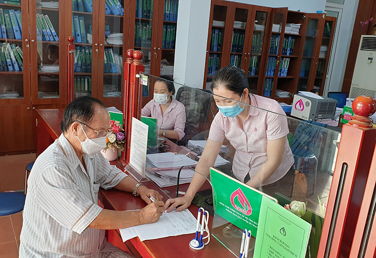 Cán bộ Phòng giao dịch NHCSXH huyện Quảng Trạch giải ngân vốn vay trả lương ngừng việc cho Công ty TNHH Sản xuất Composite Miền Trung.