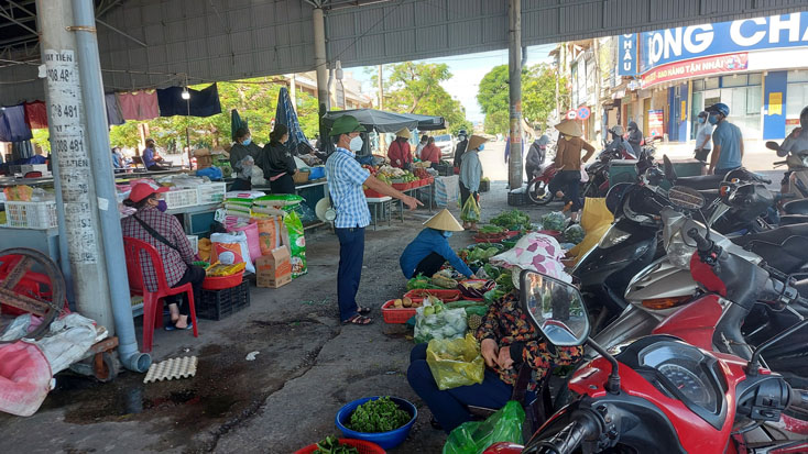 Lực lượng Ban Quản lý chợ Đồng Hới kiểm tra, hướng dẫn người dân giữ khoảng cách khi thực hiện mua bán tại chợ.