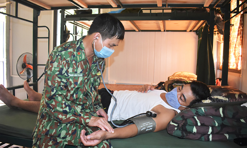 Quân y sĩ Phan Anh Tuấn khám bệnh cho bộ đội đang thực hiện nhiệm vụ tại chốt chống dịch.