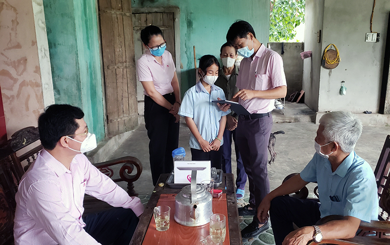 Cán bộ NHCSXH tỉnh hướng dẫn em Nguyễn Thị Kim Ngân, học sinh lớp 8 Trường THCS Quảng Hợp (Quảng Trạch) sử dụng máy tính bảng để học trực tuyến.