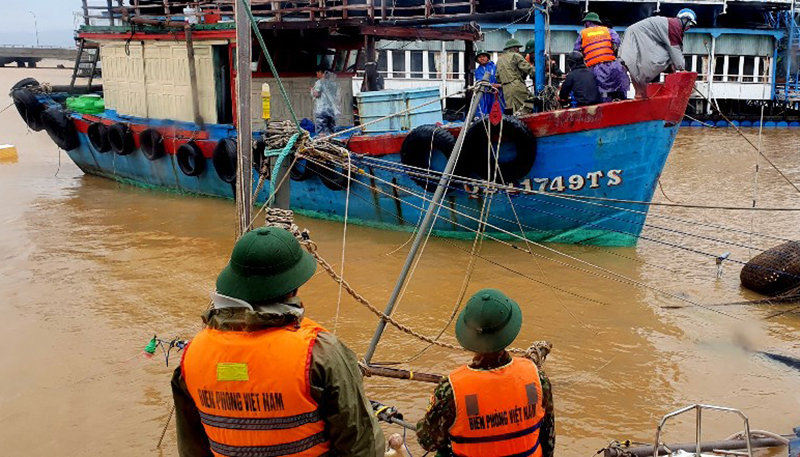 Cán bộ, chiến sĩ Đồn Biên phòng Ròon giúp ngư dân neo buộc tàu khi nước lũ dâng cao, sóng lớn. 
