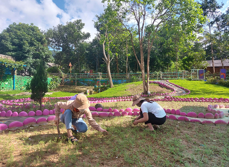 Các cô giáo ở Trường mầm non Dân Hóa chăm sóc vườn hoa trong khuôn viên trường.