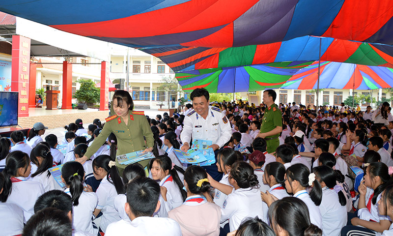 Thiếu tá Bùi Văn Sơn (giữa) phát tờ rơi tuyên truyền về tác hại của ma túy cho các em học sinh.