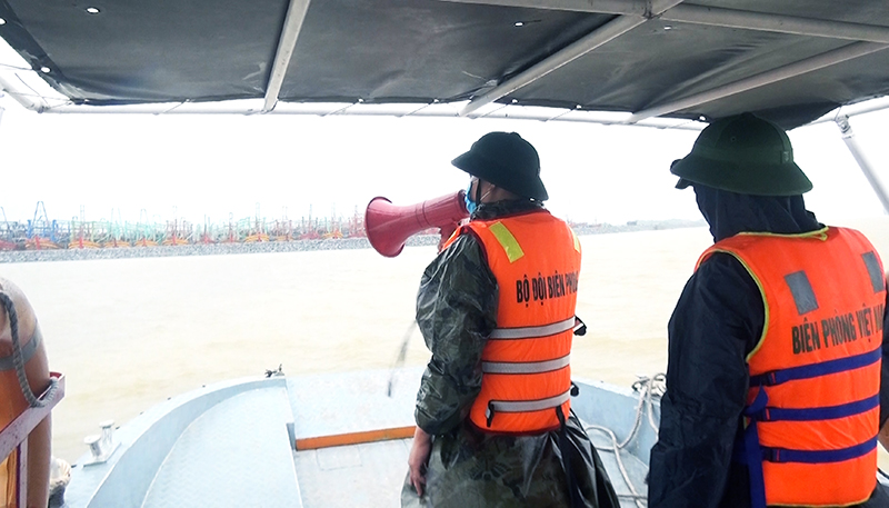 Cán bộ Đồn Biên phòng cửa khẩu cảng Gianh kêu gọi, sắp xếp tàu thuyền vào vị trí neo đậu an toàn.