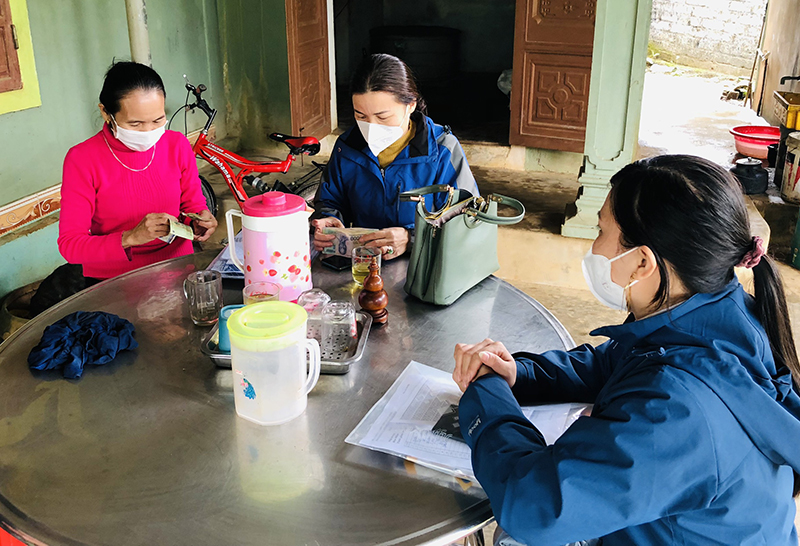 Cán bộ BHXH huyện Tuyên Hóa đến hộ gia đình vận động người dân mua BHYT.