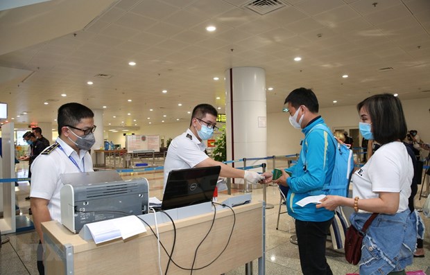 Nhân viên y tế kiểm tra phiếu khai báo y tế của hành khách trước khi làm thủ tục nhập cảnh tại cửa khẩu Sân bay quốc tế Nội Bài (Ảnh: TTXVN)