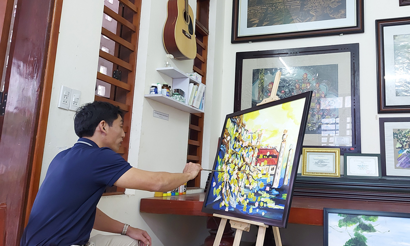 Ngoài giờ lên lớp, họa sỹ Nguyễn Thành Trung miệt mài với các bức vẽ.