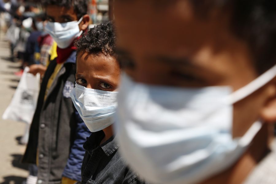 Trẻ mồ côi đeo khẩu trang nhận đồ hỗ trợ tại trại trẻ mồ côi ở Sanaa, Yemen. Ảnh: Xinhua