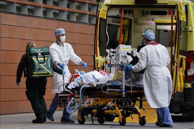 Nhân viên y tế chuyển bệnh nhân nhiễm COVID-19 tới bệnh viện ở London, Anh. Ảnh: AFP/TTXVN