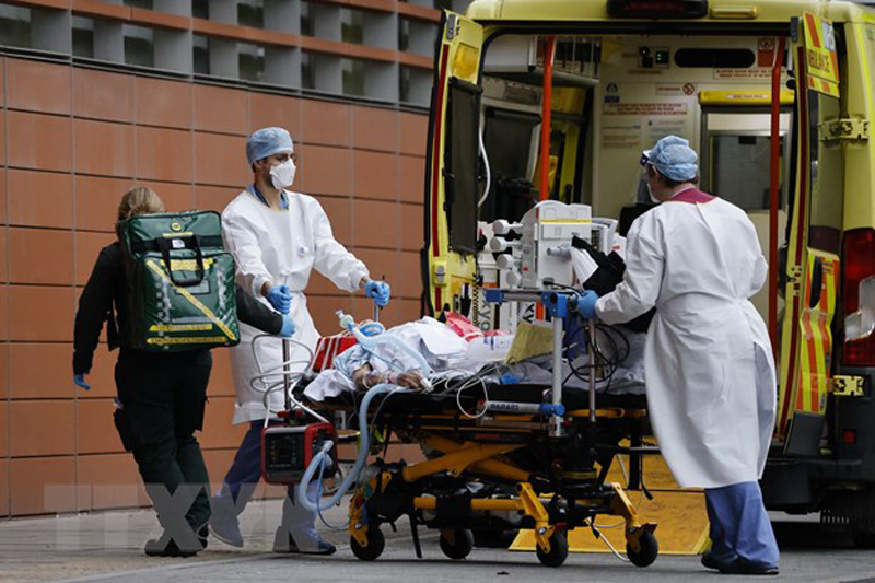 Nhân viên y tế chuyển bệnh nhân nhiễm COVID-19 tới bệnh viện ở London, Anh. (Ảnh: AFP/TTXVN)