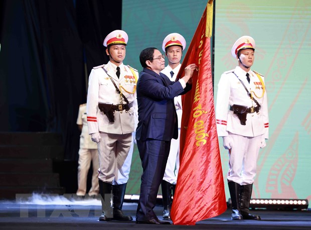 Thủ tướng Phạm Minh Chính gắn Huân chương Hồ Chí Minh lên lá cờ truyền thống của lực lượng Cảnh sát Nhân dân, Bộ Công an. (Ảnh: Phạm Kiên/TTXVN)