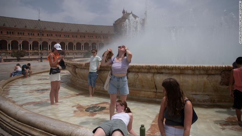 Người dân giải nhiệt ở đài phun trong đợt nắng nóng ở Seville, Tây Ban Nha. Ảnh: CNN