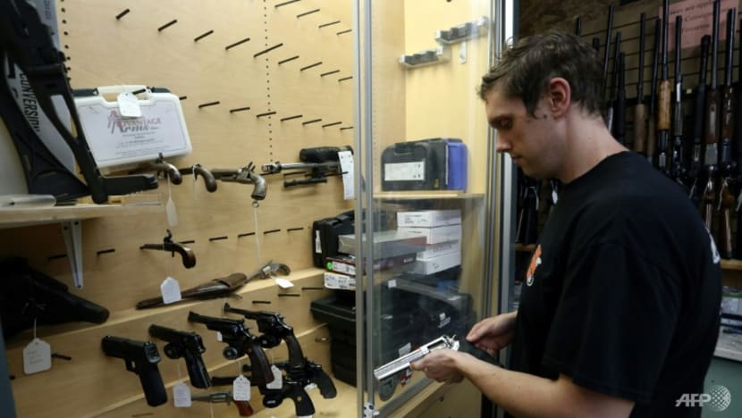 Người bán hàng lấy một khẩu súng ngắn từ một tủ trưng bày gần như trống không tại cửa hàng That Hunting Store ở Ottawa, Canada. Ảnh: AFP 