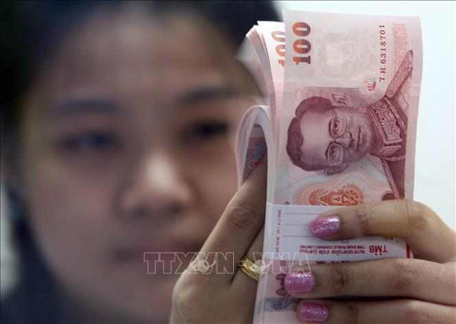 Kiểm đồng bath Thái tại một cửa hàng đổi tiền ở Bangkok. Ảnh: AFP/TTXVN