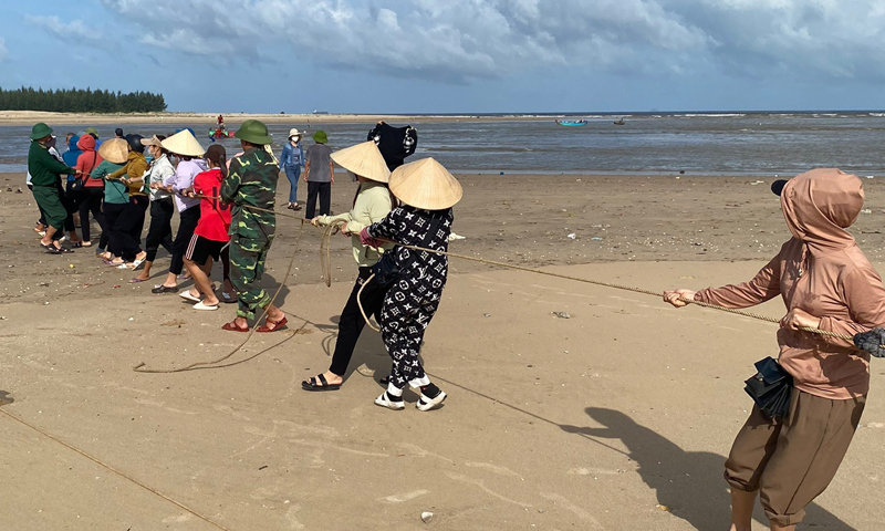 CBCS Đồn Biên phòng Ròon cùng với nhân dân hỗ trợ kéo thuyền đánh cá của anh Phạm Thanh Huân vào bờ.