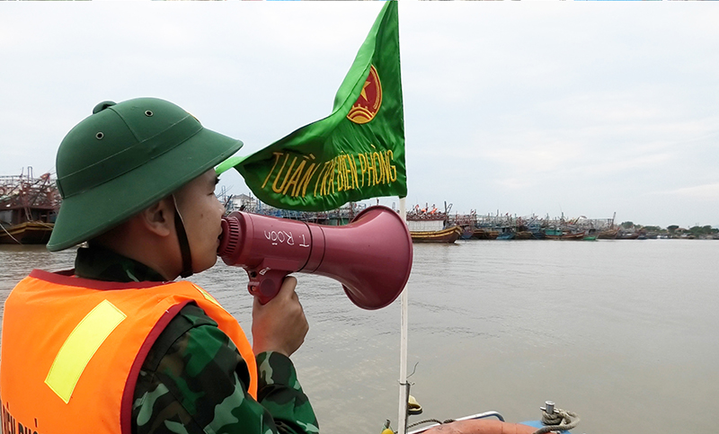 Cán bộ Đồn Biên phòng Roòn tuyên truyền cho ngư dân bằng loa thông báo trên sông và mô hình “Tiếng loa biên phòng”.