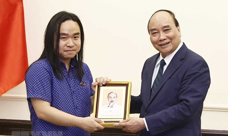 Chủ tịch nước Nguyễn Xuân Phúc tặng ảnh Chủ tịch Hồ Chí Minh cho dịch giả trẻ Nguyễn Bình. (Ảnh: Thống Nhất/TTXVN)