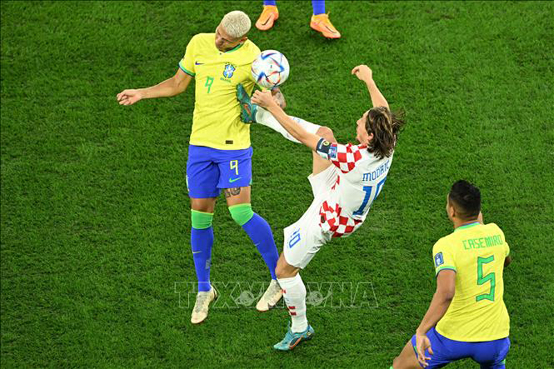 Luka Modric (phải) treo bóng từ chấm đá phạt ở khoảng cách gần 30m chếch bên cánh trái nhưng hậu vệ Brazil đã đánh đầu giải nguy cho khung thành thủ môn Alisson. Ảnh: AFP/TTXVN