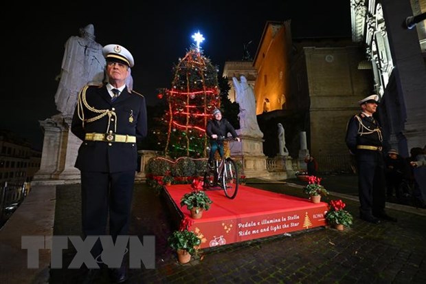 Người dân đạp xe để cung cấp năng lượng thắp sáng cây thông Noel bên ngoài Tòa thị chính Rome ở Quảng trường đồi Capitolinus , ngày 13/12. (Ảnh: AFP/TTXVN)