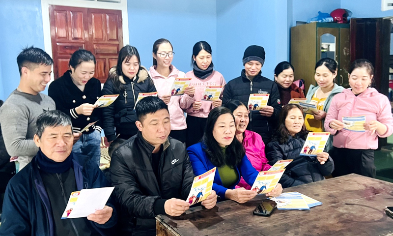 Chị Nguyễn Thị Nhường (ngồi giữa, hàng đầu) tuyên truyền về BHXH tự nguyện, BHYT hộ gia đình cho người dân.