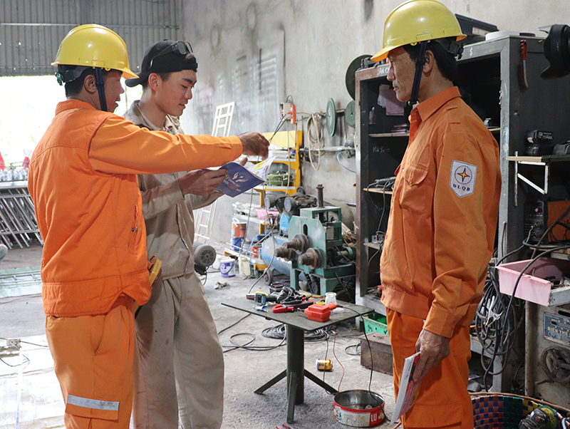 Công nhân PC Quảng Bình đang tuyên truyền pháp luật trong lĩnh vực sử dụng điện cho khách hàng