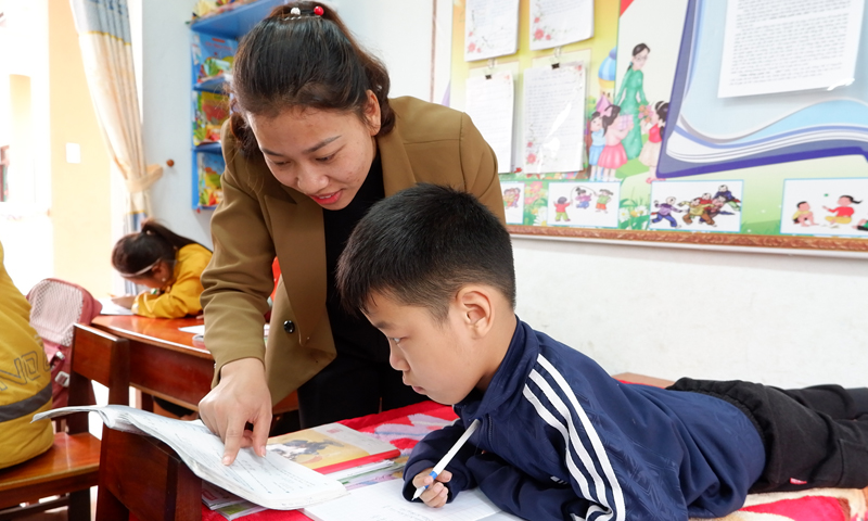Cô giáo hướng dẫn em Nguyễn Thế Phong làm bài tập.