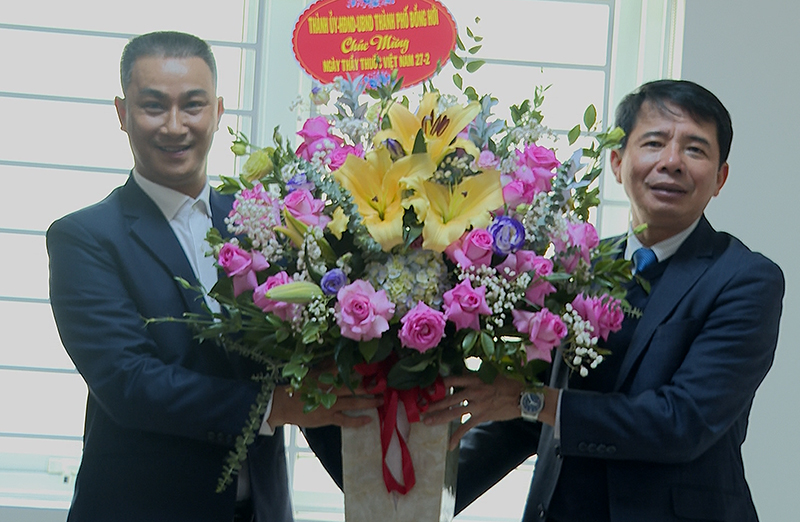 Chủ tịch UBND thành phố Hoàng Ngọc Đan tặng hoa chúc mừng cán bộ, nhân viên Phòng Y tế thành phố.
