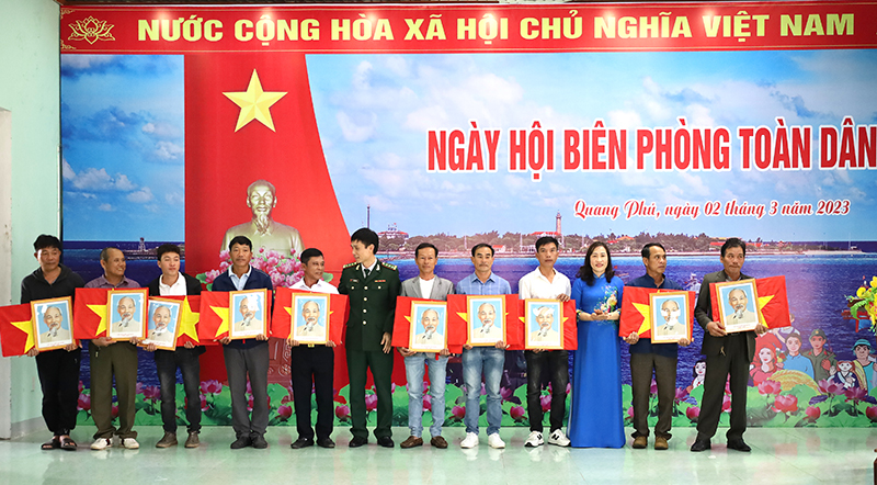 Đại diện lãnh đạo Bộ Chỉ huy Bộ đội Biên phòng tỉnh và TP. Đồng Hới tặng cờ Tổ quốc và ảnh Bác Hồ cho các đội tàu thuyền đánh bắt hải sản trên địa bàn xã Quang Phú.