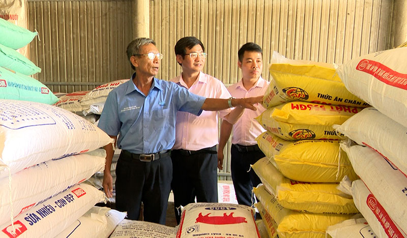 Cán bộ PGD NHCSXH huyện Bố Trạch thăm cơ sở kinh doanh thức ăn gia súc, gia cầm của gia đình ông Nguyễn Quang Trung (bên trái).