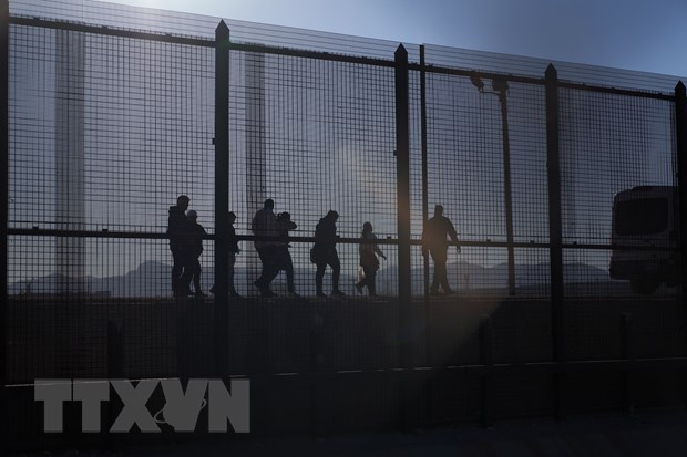 Lực lượng bảo vệ biên giới Mỹ (trái) bắt giữ người di cư trái phép tại biên giới Mexico-Mỹ, ngày 21/12/2022. (Ảnh: AFP/TTXVN)