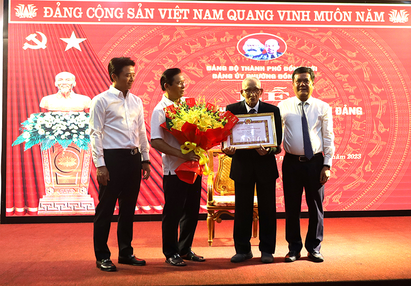 Đồng chí Bí thư Thành ủy Đồng Hới gắn Huy hiệu Đảng và tặng hoa chúc mừng đồng chí Võ Xuân Khảng.
