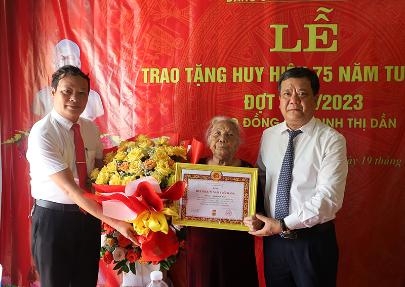 Đồng chí Bí thư Thành ủy Đồng Hới trao Huy hiệu Đảng và tặng hoa chúc mừng đồng chí Đinh Thị Dần.