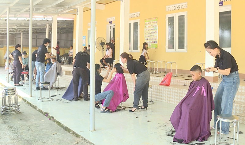 Các đoàn viên, thanh niên Câu lạc bộ Làm đẹp thị trấn Nông trường Việt Trung tham gia cắt tóc miễn phí cho các em nhỏ tại bản Khe Ngát (thị trấn Nông trường Việt Trung, Bố Trạch).
