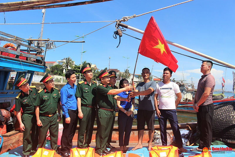 Đại tá Đoàn Xuân Bường, Phó Chính ủy Quân khu 4 cùng đoàn đại biểu tặng cờ Tổ quốc và áo phao cho bà con ngư dân Quảng Bình.