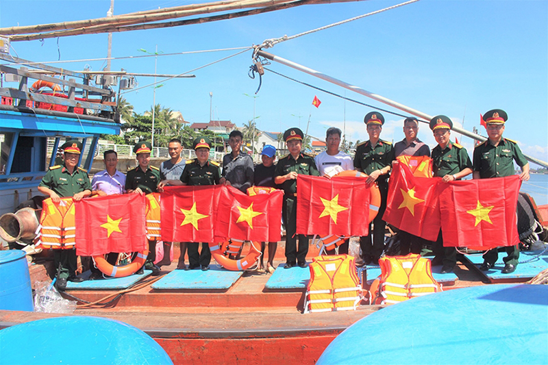 Ban tổ chức trao cờ Tổ quốc, áo phao tặng ngư dân cảng cá Nhật Lệ (Đồng Hới, Quảng Bình). 