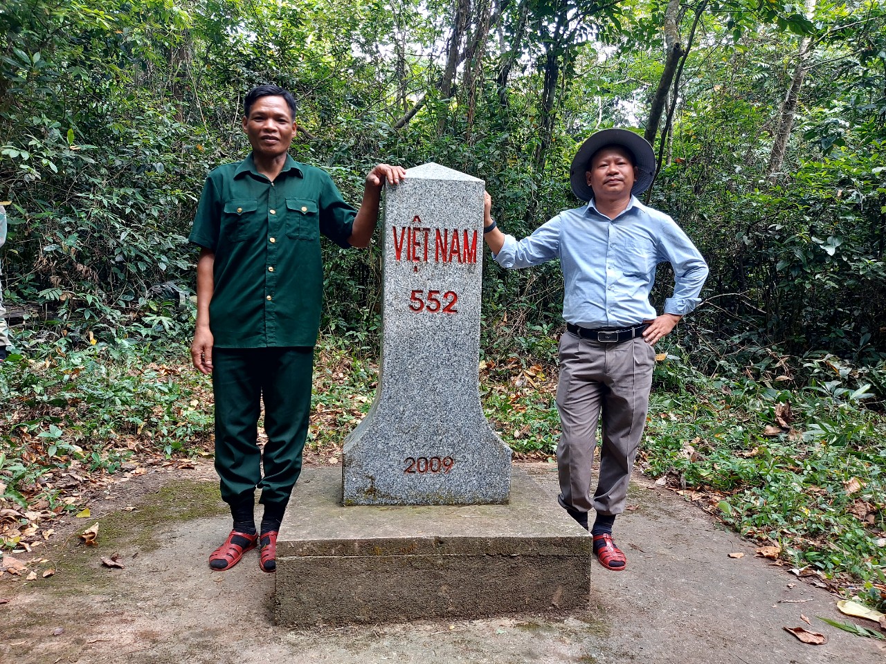 Ông Hồ Bang (áo xanh) ở bản Dốc Mây (xã Trường Sơn) chụp ảnh lưu niệm bên mốc quốc giới số 552.