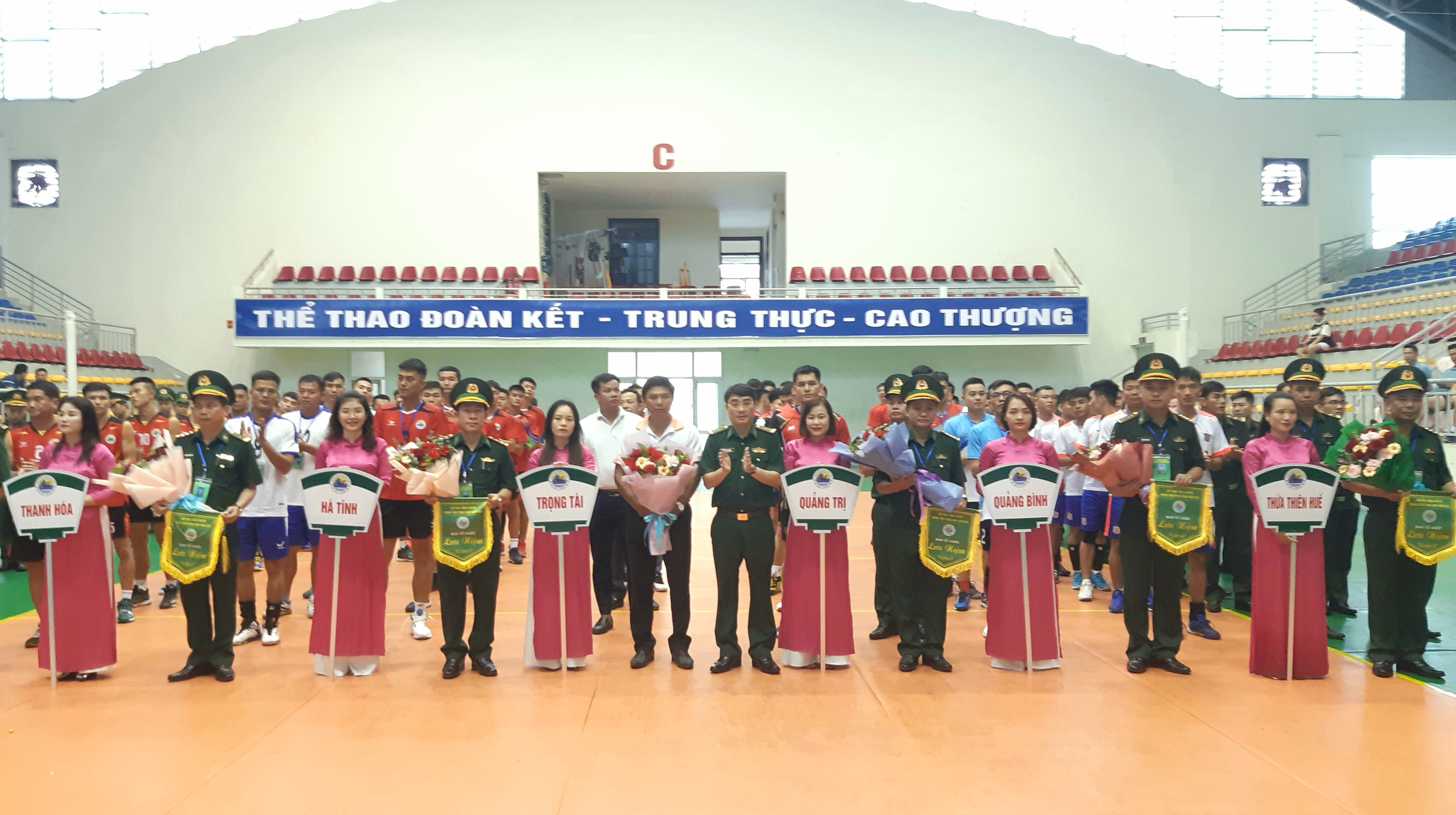 Đại tá Hồ Thanh Sơn Phó Chỉ huy trưởng, Tham mưu trưởng BĐBP tỉnh (ở giữa) tặng hoa và cờ lưu niệm cho các đội tham dự khai mạc Hội thao bóng chuyền Bảng C khu vực I.