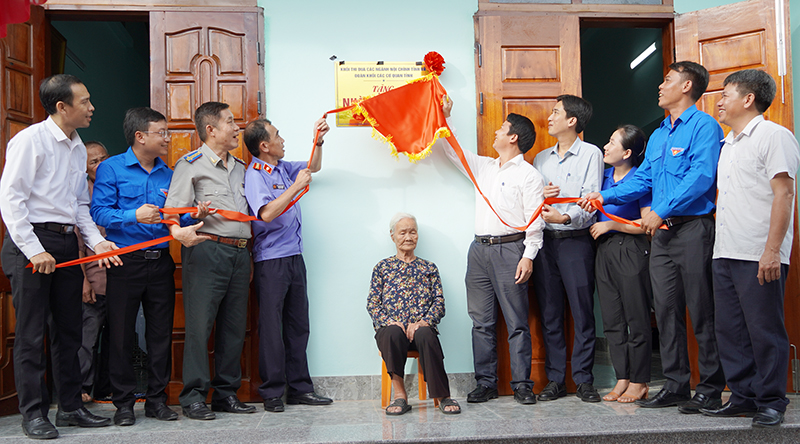 Các đại biểu và đại diện gia đình kéo băng khánh thành nhà tình nghĩa.