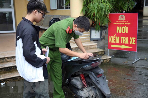 Cán bộ Công an thị trấn Trâu Quỳ, huyện Gia Lâm lấy số khung, số máy cho người dân đăng ký làm thủ tục đăng ký xe máy. (Ảnh: Phạm Kiên/TTXVN)