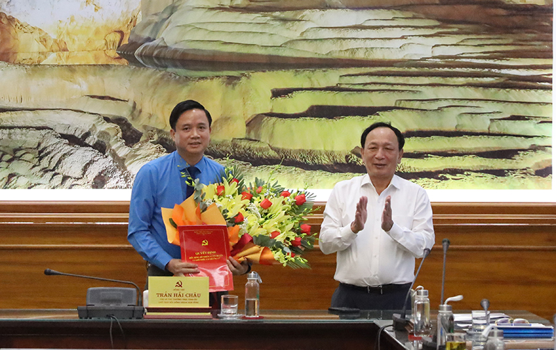 Đồng chí Phó Bí thư Thường trực Tỉnh ủy Trần Hải Châu phát trao quyết định và tặng hoa chúc mừng đồng chí Chủ tịch LĐLĐ tỉnh Phạm Tiến Nam.