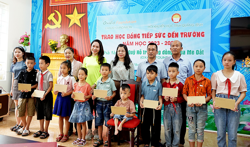 Đại diện nhà tài trợ và các thầy cô giáo trao học bổng cho các em học sinh trên địa bàn huyện Bố Trạch.