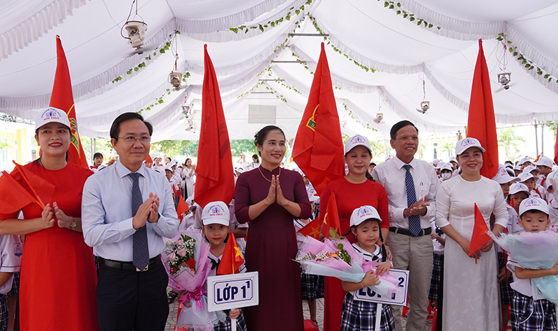 Đồng chí Phó Chủ tịch HĐND tỉnh Hoàng Xuân Tân cùng đại diện lãnh đạo huyện Lệ Thủy, chính quyền địa phương tặng hoa cho học sinh mới vào lớp 1.