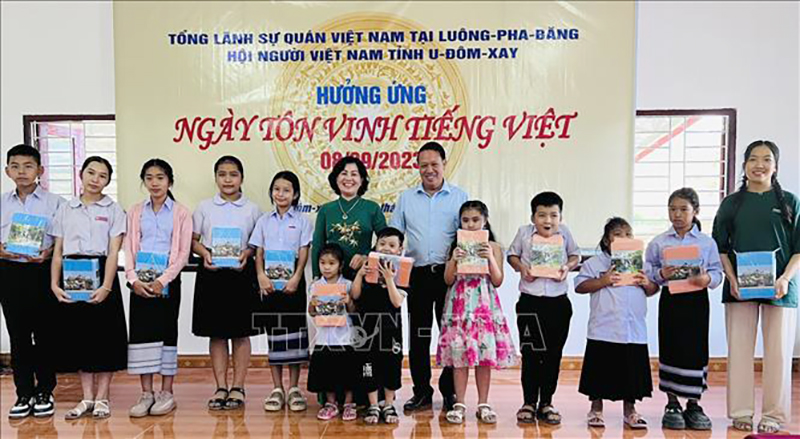  Tổng Lãnh sự Việt Nam tại Luang Prabang, bà Kiều Thị Hằng Phúc (áo dài xanh) chụp ảnh lưu niệm cùng con em cộng đồng người Việt Nam và Lào có hoàn cảnh khó khăn nhân dịp khai giảng năm học mới. Ảnh: TTXVN phát